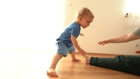 A young woman and her little son do gymnastics on the floor at home during a covid-19 lockdown. Stretching, funny video kid repeats after mom