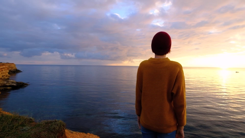 Young woman relaxing meditating alone on sea beach at colorful sky background. Stress overcome