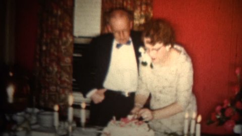 MINNEAPOLIS, MINNESOTA - OCTOBER 1958: An old couple celebrating their 50th wedding anniversary with a simple cake.