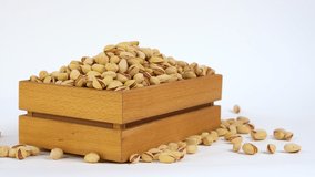 Pistachio nuts in wooden box. Nuts on white background. Slider shot. Free space for text. Video set for footage. Products show for sale. Fresh roasted pistachio nuts in wooden box.