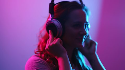 Young woman listens to music on her headphones - stylish illuminated - videoclip