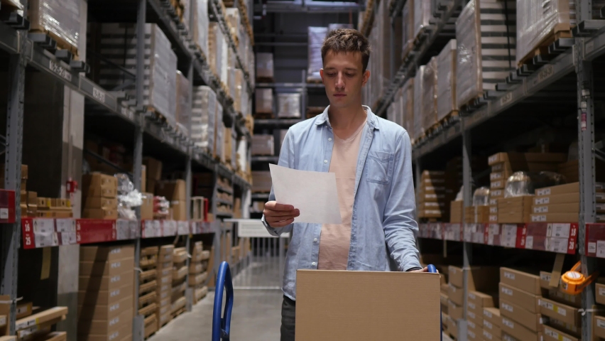 Confident young middle-aged man, retail shopper, entrepreneur walking through the warehouse looking for the right box of goods. The concept of shopping, renovation, new furniture Royalty-Free Stock Footage #1064530213