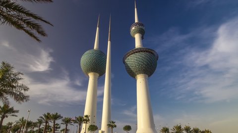 The Kuwait Towers timelapse hyperlapse - the best known landmark of Kuwait City. View with palms and flowerbed, blue cloudy sky before sunset. Kuwait, Middle East
