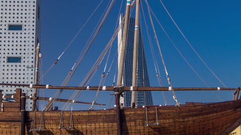 Historic dhow ships timelapse hyperlapse near museum in Kuwait. Skyscrapers on background with blue sky. Kuwait, Middle East.