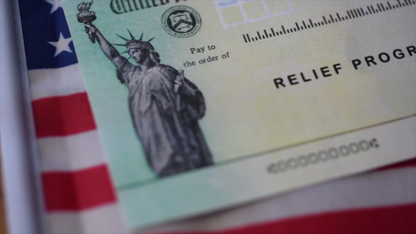 Blurring Stimulus relief program check (Economic Impact Payment) on American flag background. Close up view.  Royalty-Free Stock Footage #1064536924