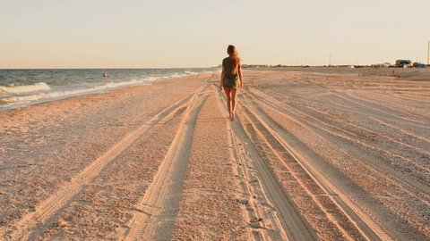 sexy sensual young skinny woman walks on the beach along the seashore. A woman in a shirt and thong bikini panties ocean lifestyle