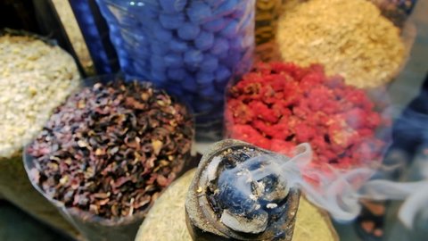 United Arab Emirates - 2 May, 2020 - Deira Spice Souk, Historical Center of Dubai. Oriental incense burning in mabkhara. Aromatic smoke spreading out. Unknown man putting spicy into jar. Closeup shot