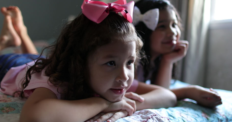 Children watching movie at home, girls lie in bed hypnotized by screen | Shutterstock HD Video #1064544919
