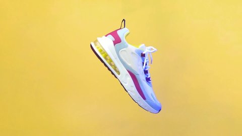 Spinning sports shoe concept, white shoes with a blend of colorful lines. Sport shoe rotation isolated on yellow background. Blue and red lighting from the side of the shoe. illustration of sport shoe