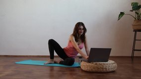 Attractive young woman exercising while resting at home. View of a woman conducting virtual fitness class at home on a video conference. Repeating exercise in online class