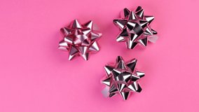 Three silver gift bows spinning on a pink background - Powered by Shutterstock - Get 15% off with code: PIKWIZARD15