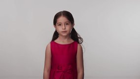 Girl in little red dress looking at the camera. Portrait beautiful little girl looking at camera.Slow motion video.