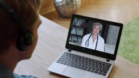 Man having video conferencing with online woman doctor. Remote patient consulting video call in conference virtual webcam chat app. Over shoulder laptop screen view.