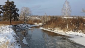 Aerial video of Koen river under ice and snow. Beautiful winter landscape. Novosibirsk, Siberia, Russia