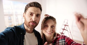 POV of happy lovely Caucasian family couple standing in apartment with big window videochatting on webcam, waving hands and smiling. Video call online. Home renovation. Close up concept