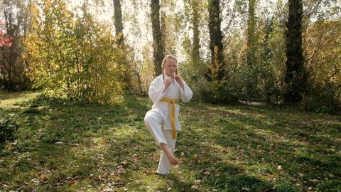 teenager girl 12 years old is engaged in karate outdoors in the park. Healthy lifestyle concept. playing sports. martial arts. Judo, Jiujitsu. bold, strong. does a leg workout. workouts