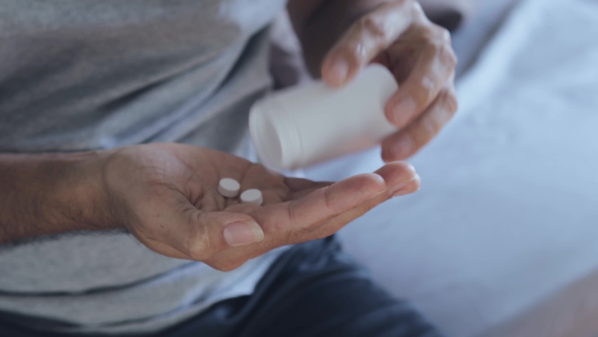 Young man poured the medicine out of the bottle and counted. | Shutterstock HD Video #1064595916