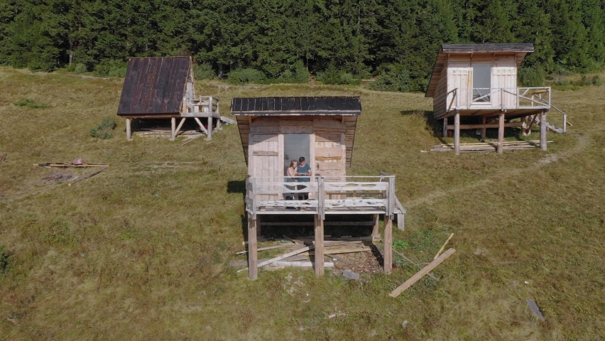 Hikers couple standing outdoors near wooden house in the mountains