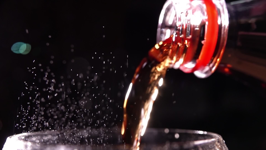 Pouring cola into a glass. Filling glass with fizzy cola. Lens light reflections in close up slow motion shot 500FPS  Glass of Cola with fizzy baubles isolated on black background Royalty-Free Stock Footage #1064607415