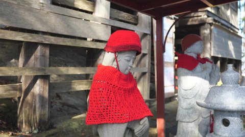 Jizo of a shrine wearing hand-knitted red yarn. Wearing a yarn hat. Jizo is known as the guardian deity of children in the Japanese culture. Asian culture and tradition. Winter season