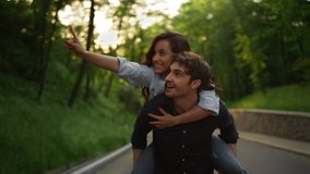 Closeup smiling man carrying woman piggy back outdoors. Happy couple having fun during walk at romantic date in summer park. Joyful couple piggyback on park road and feeling happiness at sunset. - Powered by Shutterstock - Get 15% off with code: PIKWIZARD15