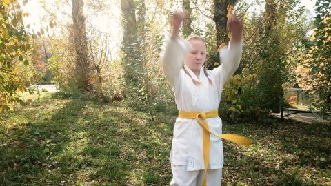 teenager girl 12 years old is engaged in karate outdoors in the park. Healthy lifestyle concept. playing sports. martial arts. Judo, Jiujitsu. bold, strong. does a warm-up of the arms. workouts