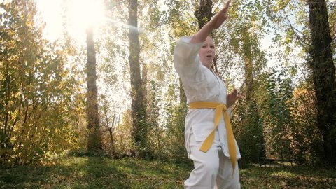 teenager girl 12 years old is engaged in karate outdoors in the park. Healthy lifestyle concept. playing sports. martial arts. Judo, Jiujitsu. bold, strong. practicing various stances and exercises.