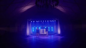 Musical band group of three people playing song, performing on concert musician stage with lights. Shooting a music video. Singer vocalist girl, saxophonist sax, dj man. Actors dancing, singing