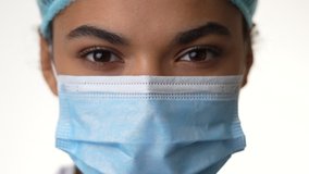 Trusted doctor. Close up of attractive young female doctor taking off her medical mask isolated over white background. Healthcare and medicine concept. Slow motion