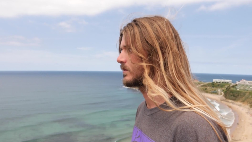 cross-eyed man blond with long hair on the beach