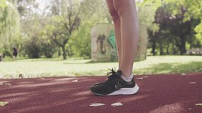 Fitness girl on an all weather synthetic track surface in the park. Close up abstract video of legs running.