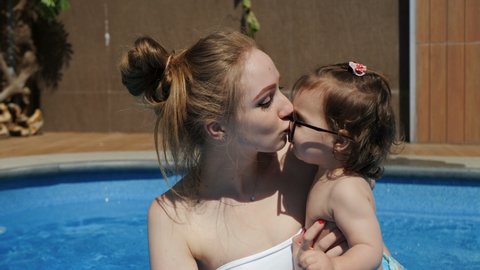 Mother and little daughter in open pool on summer vacation