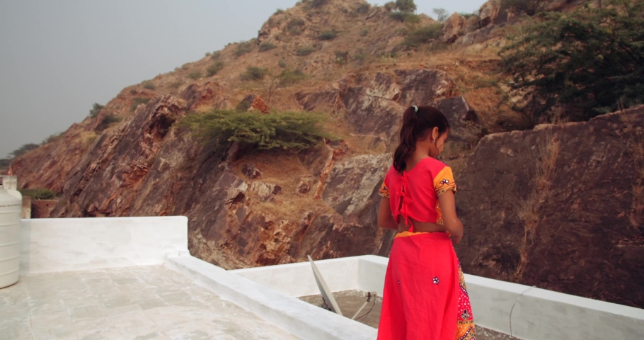 Slow-motion close-up CU portrait of a young female child wearing colorful dress taking selfie photo video using smart phone mobile communication technology digital device on roof terrace house