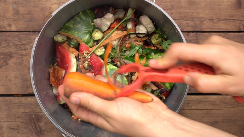 Housewife throws vegetable peeling, scraps and fruit peels in compost bucket. Top view. Organic kitchen home waste gathering for composting. Separation and recycling of household garbage, Zero waste Royalty-Free Stock Footage #1064653864