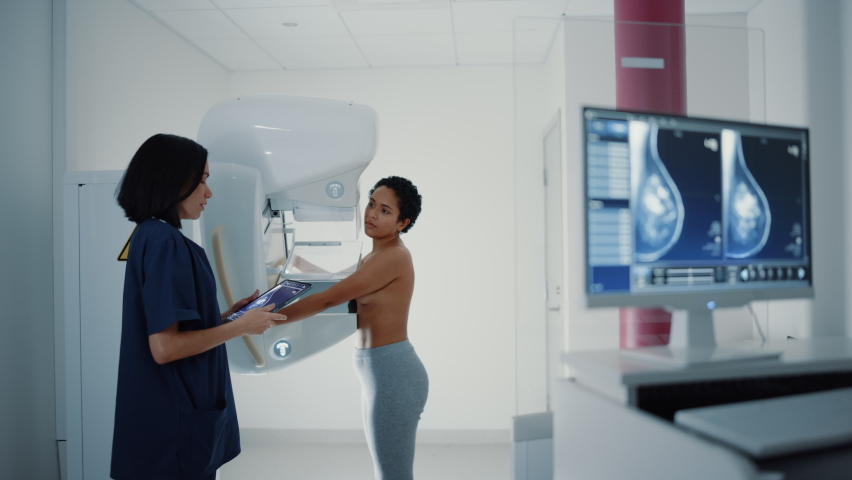 Computer Screen in Hospital Radiology Room: Beautiful Multiethnic Young Woman Standing Topless Undergoing Mammography Screening Procedure. Screen Showing the Mammogram Scans of Dense Breast Tissues. Royalty-Free Stock Footage #1064654440