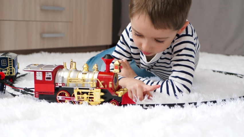 Little boy playing with toy railway lying on the floor. The children are playing. Happy childhood. entertainment at home