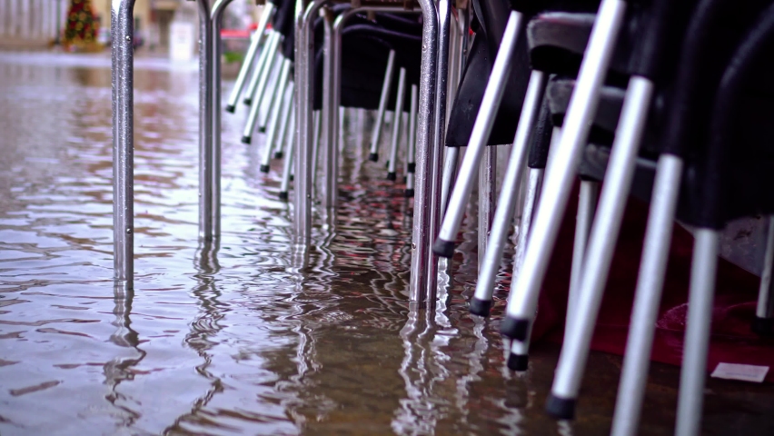 Folded leather chairs of street cafe stand in flood water