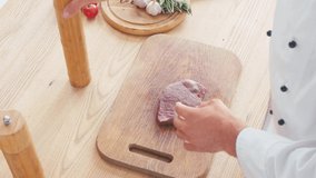 Cropped view of chef with mill seasoning beef steak on chopping board
