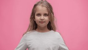Close up portrait of little girl making eyes at pink background. Cute curly-haired girl with puppy eyes and begging look asking parents to buy a new toy.