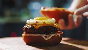 cooking burgers. Close-up. Big appetizing burger with fresh cucumbers, tomatoes, juicy, grilled beef patty with cheese, and fried egg on top. fast food, junk food. - Powered by Shutterstock - Get 15% off with code: PIKWIZARD15