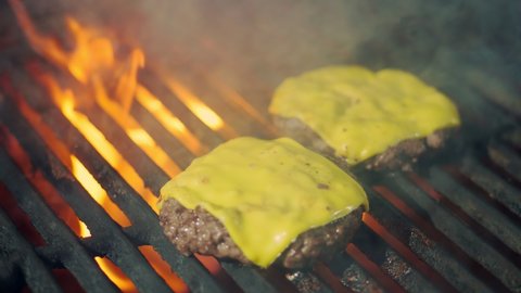 cookery. cooking burgers. Close-up. grilling of fresh meat burger patties with yellow melted cheese on brazier. roasting process of beef meat medallions on hot flame barbecue grill. fast food, junk