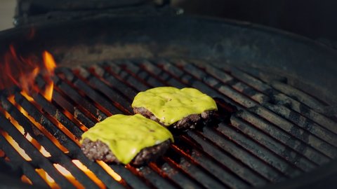 cookery. cooking burgers. Close-up. grilling of fresh meat burger patties with yellow melted cheese on brazier. roasting process of beef meat medallions on hot flame barbecue grill. fast food, junk