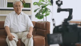Family concept of 4k Resolution. An elderly Asian man is giving an interview about his health in the living room.