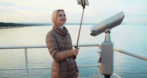
Cheerful Pretty Woman Talking on Video Communication via Smartphone While Standing on the Pier. Female Blogger, a Social Media Influencer, Talks to her Followers on Camera about her Journey.
