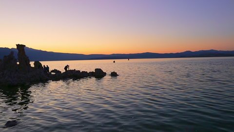 photographer silhouette reflecing on the smooth waters of Mono Lake, one of the oldest lakes in North America. The Mono Lake Tufa State Natural Reserve, California, United States. Sunset shot.