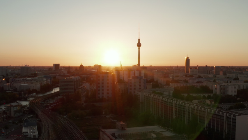 Aerial Drone Flight over Berlin, Germany at beautiful Golden Hour Sunset, Sunlight and view on Alexanderplatz TV Tower, Sunflairs circa 2019