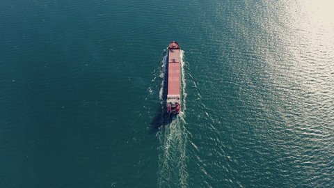 Aerial view of ultra large tanker ship sailing on calm sea on sunny and warm summer day. Concept of cheap shipping by sea, top down view. Drone 4k high quality footage