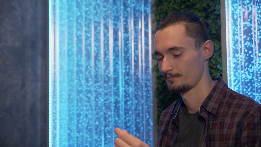 Close up of man smoking traditional hookah pipe and making smoke clouds in a form of rings.