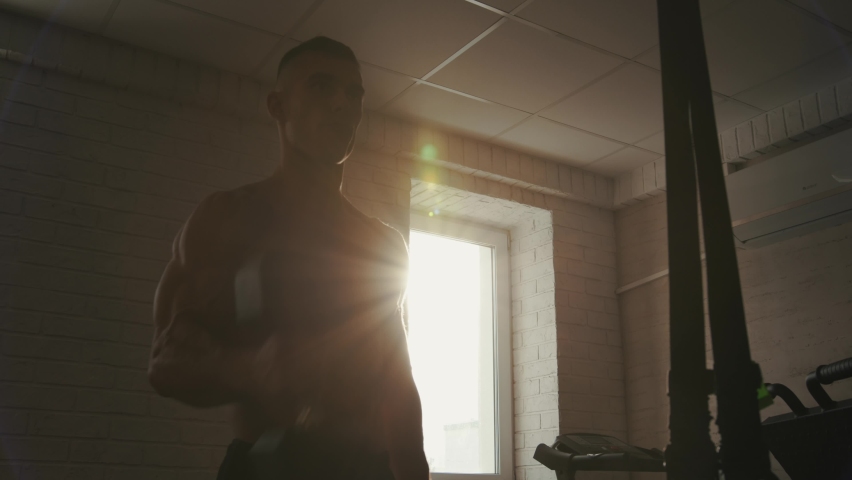 A young bodybuilder with a naked torso training in the gym and does exercise plank and body turns for pumping core muscles