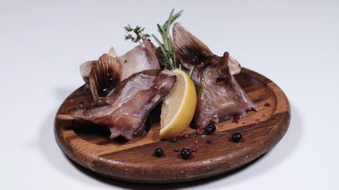 Pieces of smoked fish on a wooden plate. Delicious beer snack. Rotates on a plate. Cyclic motion